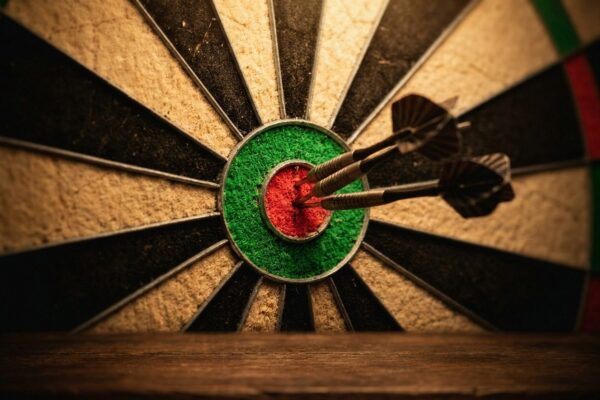 Drei Steeldarts stecken im Bullseye einer Sisal-Dartscheibe